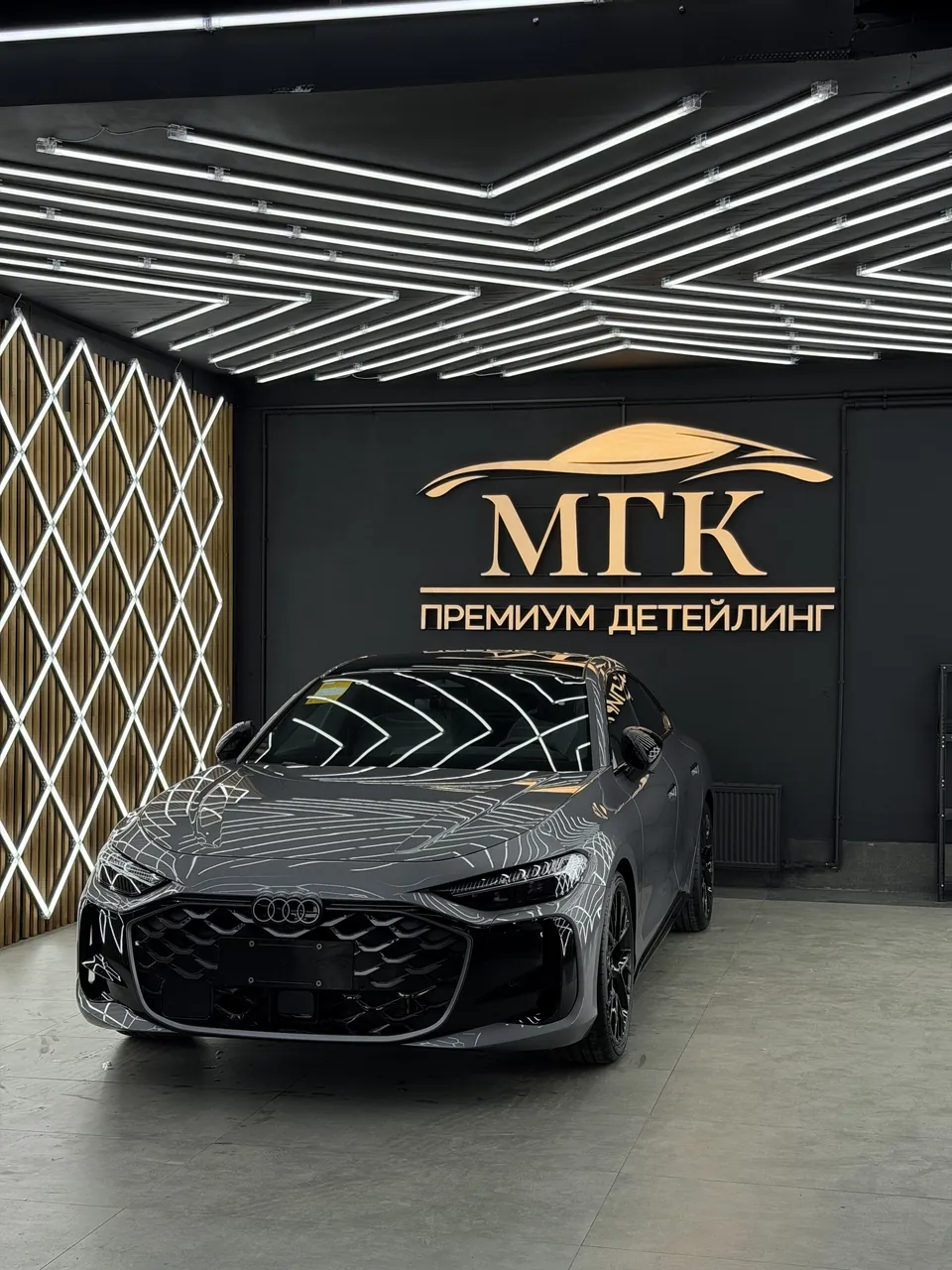 Серый Audi после детейлинга на фоне фирменной стены МГК