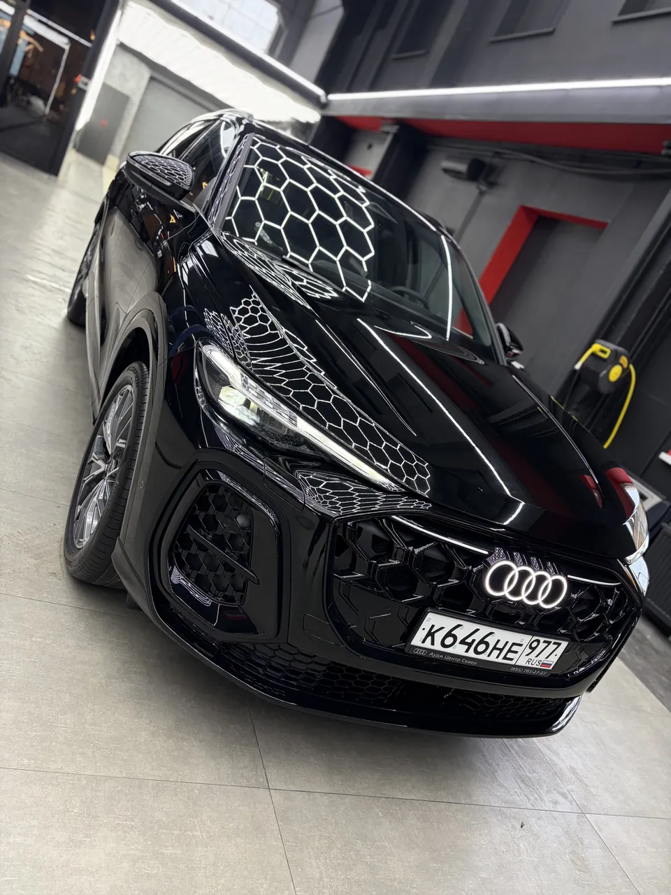 Чёрный кроссовер Audi после детейлинга, вид спереди в рабочем боксе