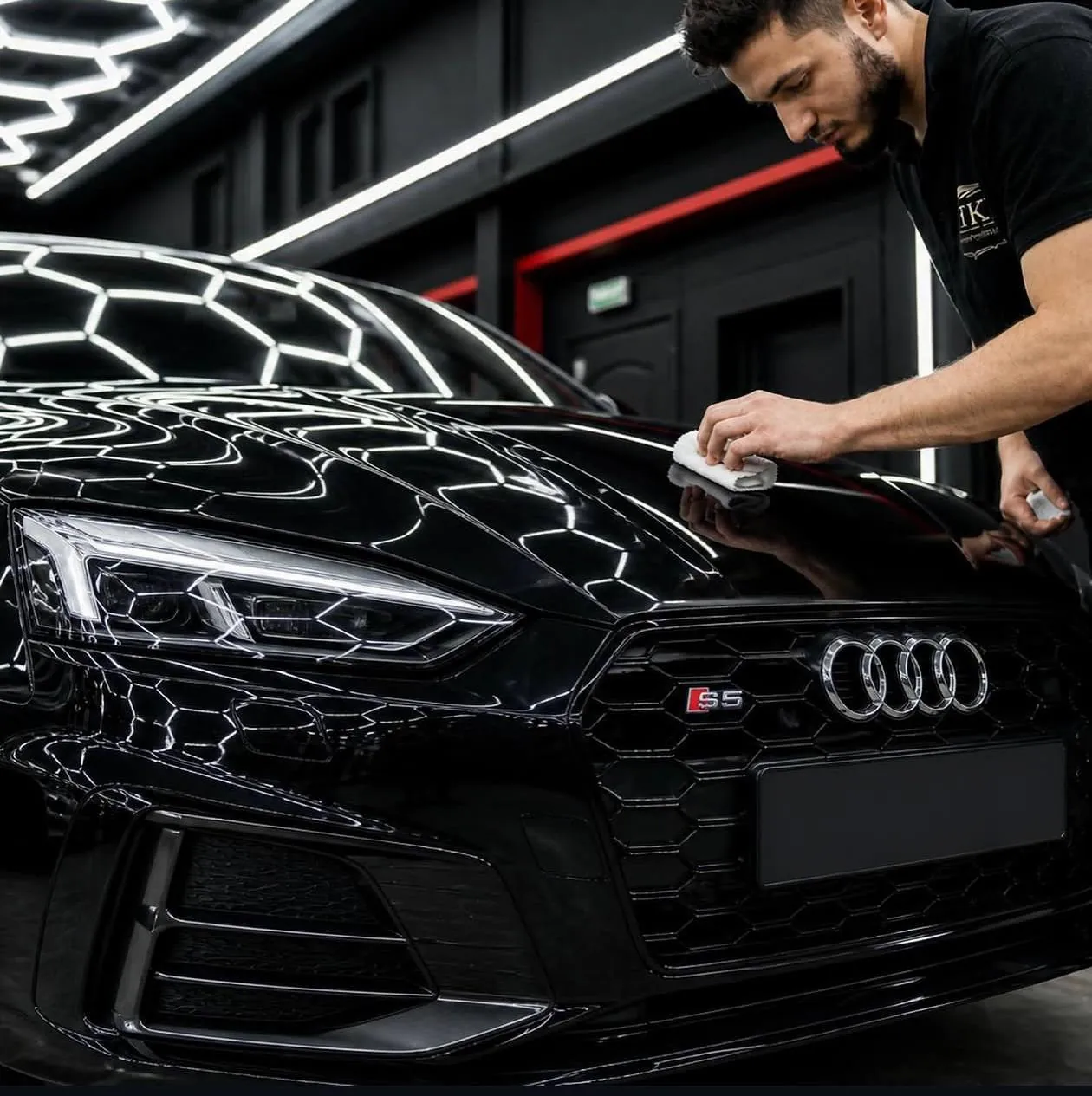 Мастер вручную наносит защитный состав на капот чёрного Audi S5