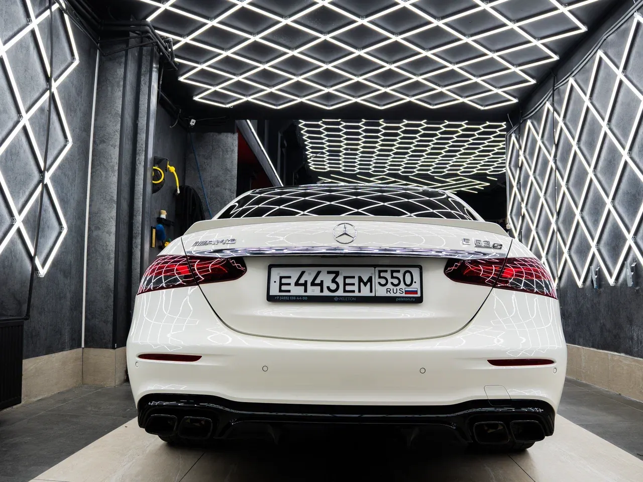 Белый Mercedes-AMG E 63 S после детейлинга, вид сзади в световом боксе